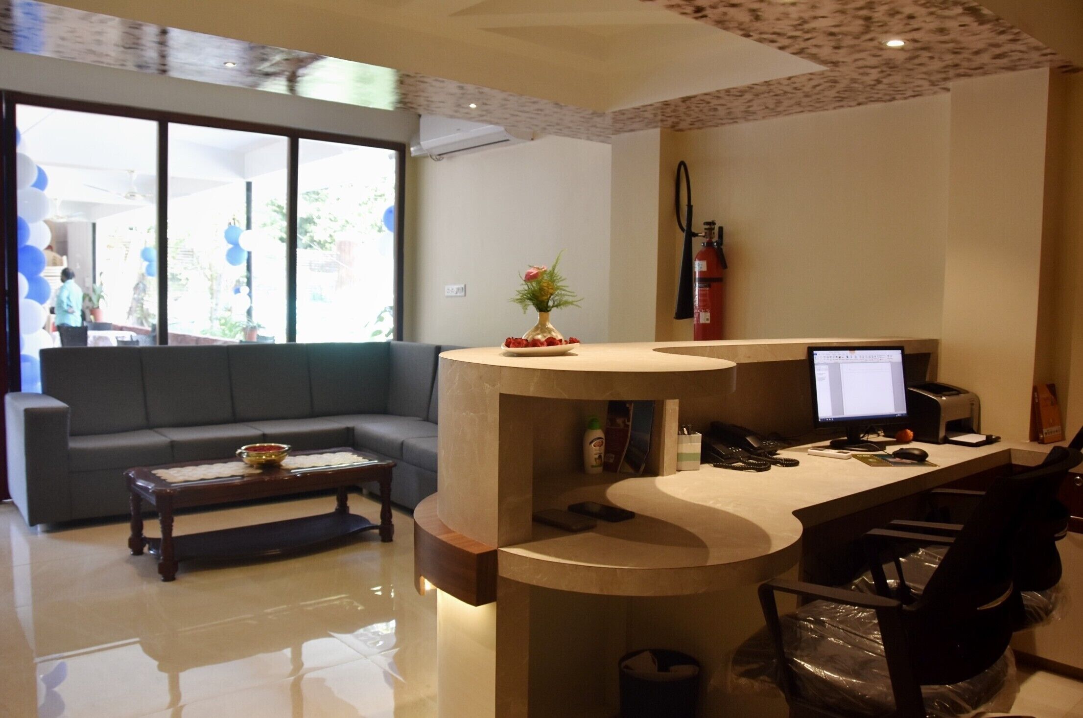 A modern reception area with a curved desk, a computer, a sofa, and a coffee table.
