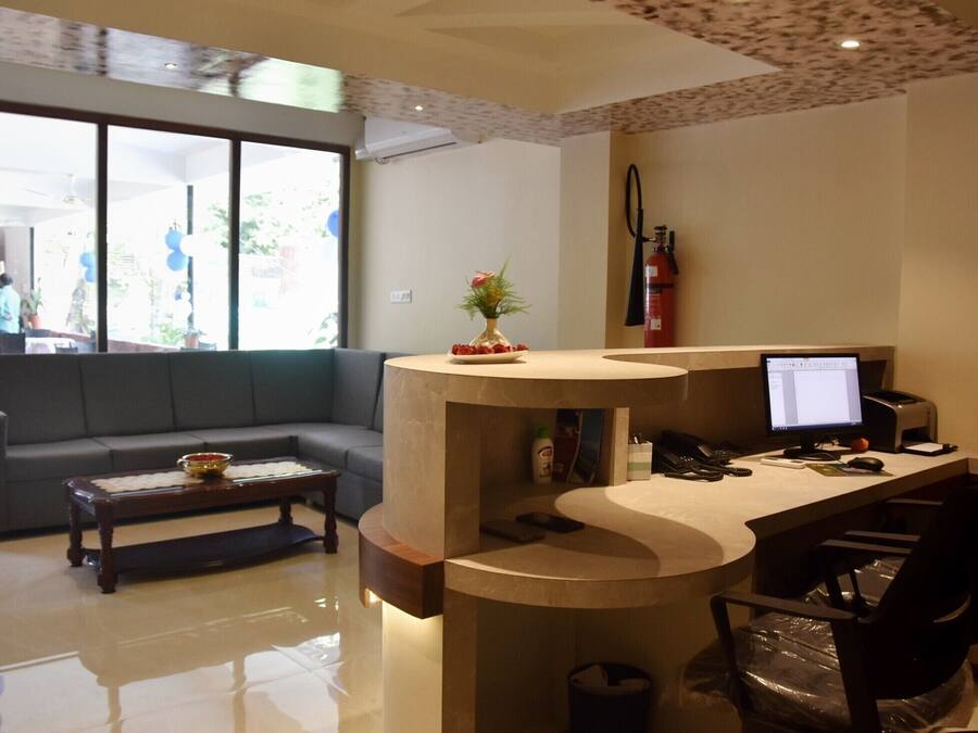 A modern reception area with a curved desk, a computer, a sofa, and a coffee table.