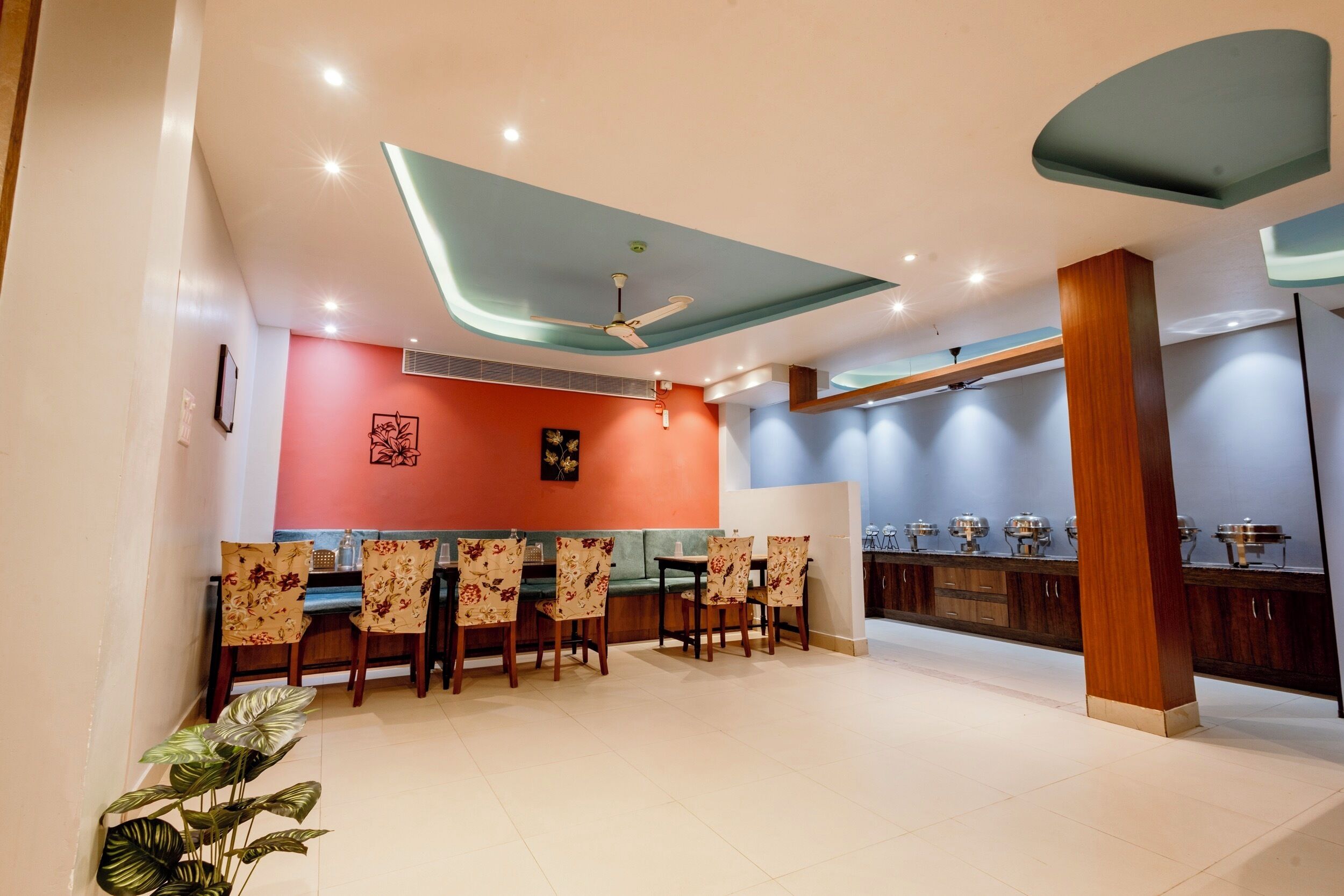 A modern dining area with a high ceiling, recessed lighting, and a central ceiling fan.