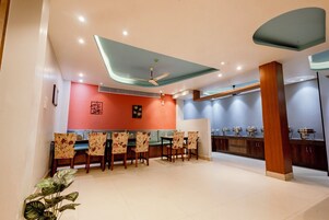 A modern dining area with a high ceiling, recessed lighting, and a central ceiling fan.