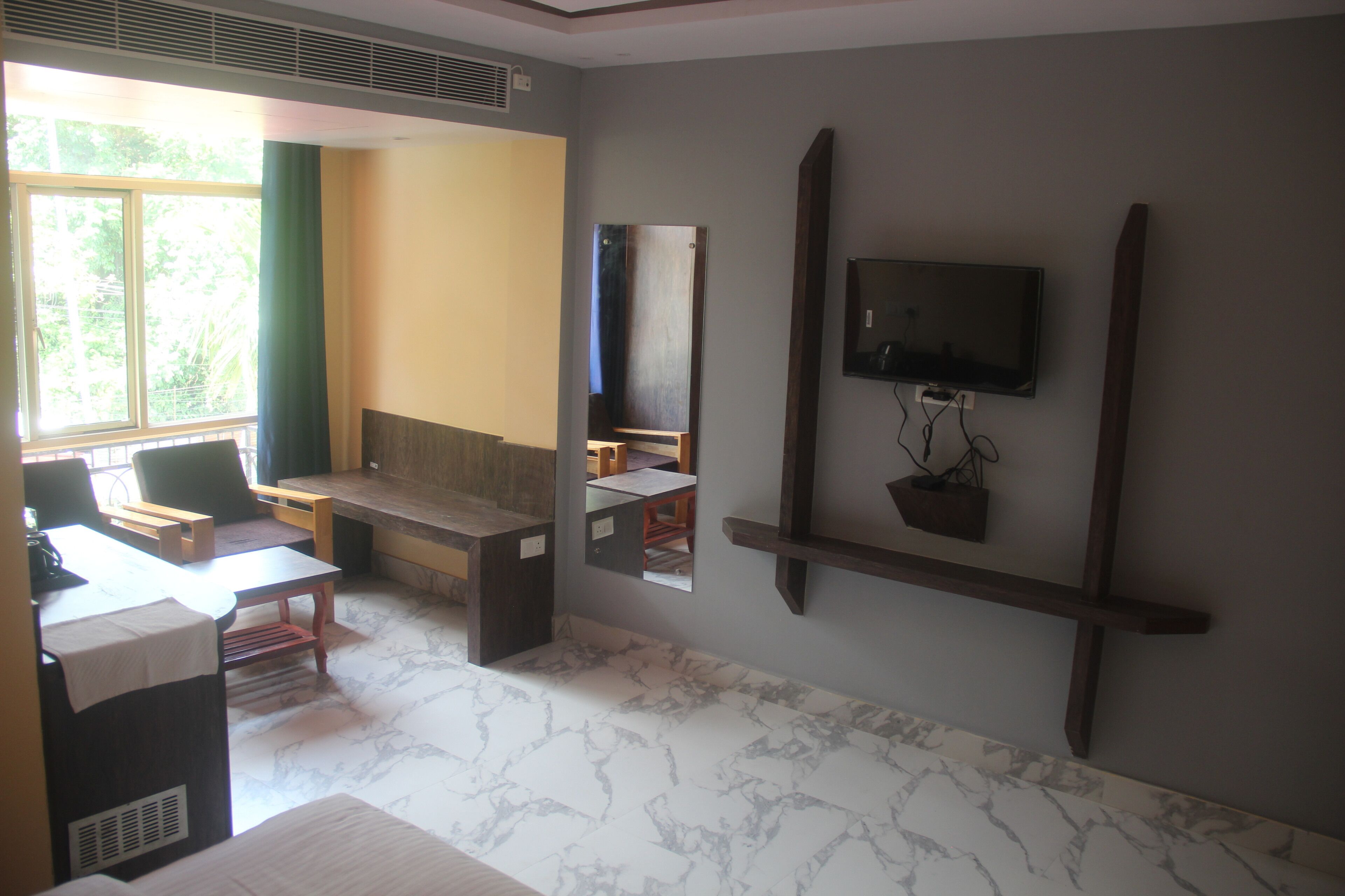 A room with a desk, chair, and a television mounted on the wall.