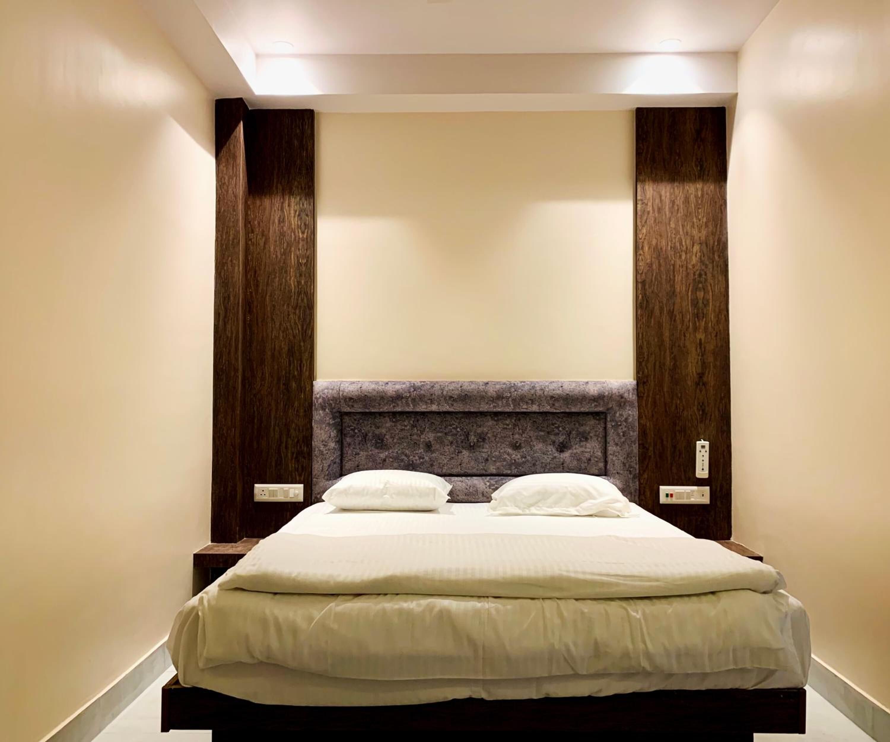 Una habitación de hotel con una cama grande, cabecera de madera y dos mesitas de noche.