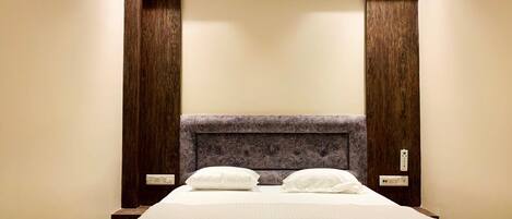 Una habitación de hotel con una cama grande, cabecera de madera y dos mesitas de noche.