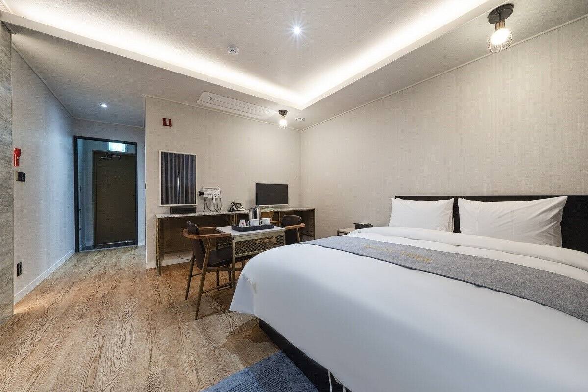 A modern hotel room with a large bed, a desk with a computer, and a television.
