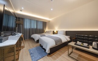 Una habitación de hotel moderna con dos camas, un escritorio, cafetera y televisión.
