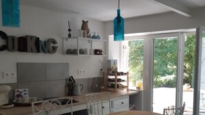 A modern kitchen with white cabinets, a wooden countertop, and a dining area with white chairs. - Lake view Lodge chambon Eguzon  <br>Beautiful  Lake Views  (Éguzon-Chantôme)