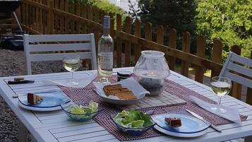 A table set outdoors with plates, glasses, and a bottle, overlooking a lake.