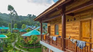 A wooden cabin with a balcony, surrounded by lush greenery and other cabins in the background. - Valley Sen Bungalow (Phu Quoc)