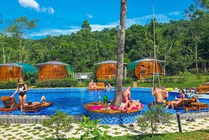 A pool area with wooden cabanas, lounge chairs, and a central circular platform. - Valley Sen Bungalow (Phu Quoc)