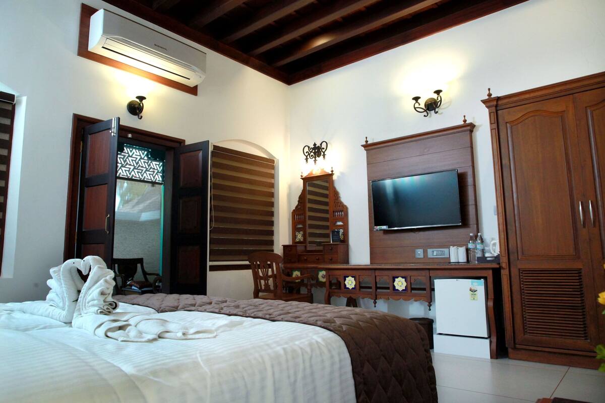 Une chambre d’hôtel équipée d’un lit, d’une télévision, d’une armoire, d’un bureau et d’un appareil de climatisation.