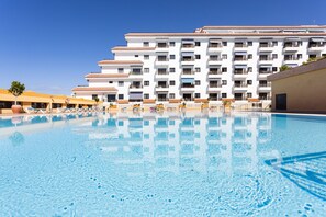 Un hotel con piscina, varios balcones y un cielo azul despejado.