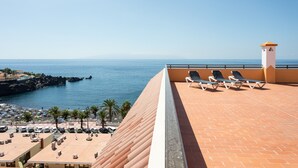 Una terraza en la azotea con sillones de descanso y vistas al mar.