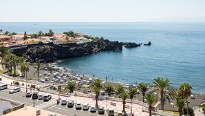 Un pueblo costero con playa, automóviles y palmeras.