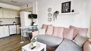 Una sala de estar moderna con un sofá blanco, una mesa de centro y una cocina al fondo.