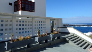 Un bâtiment moderne à la façade blanche, doté de nombreuses fenêtres et d’un escalier menant à un balcon d’où l’on a vue sur la mer.