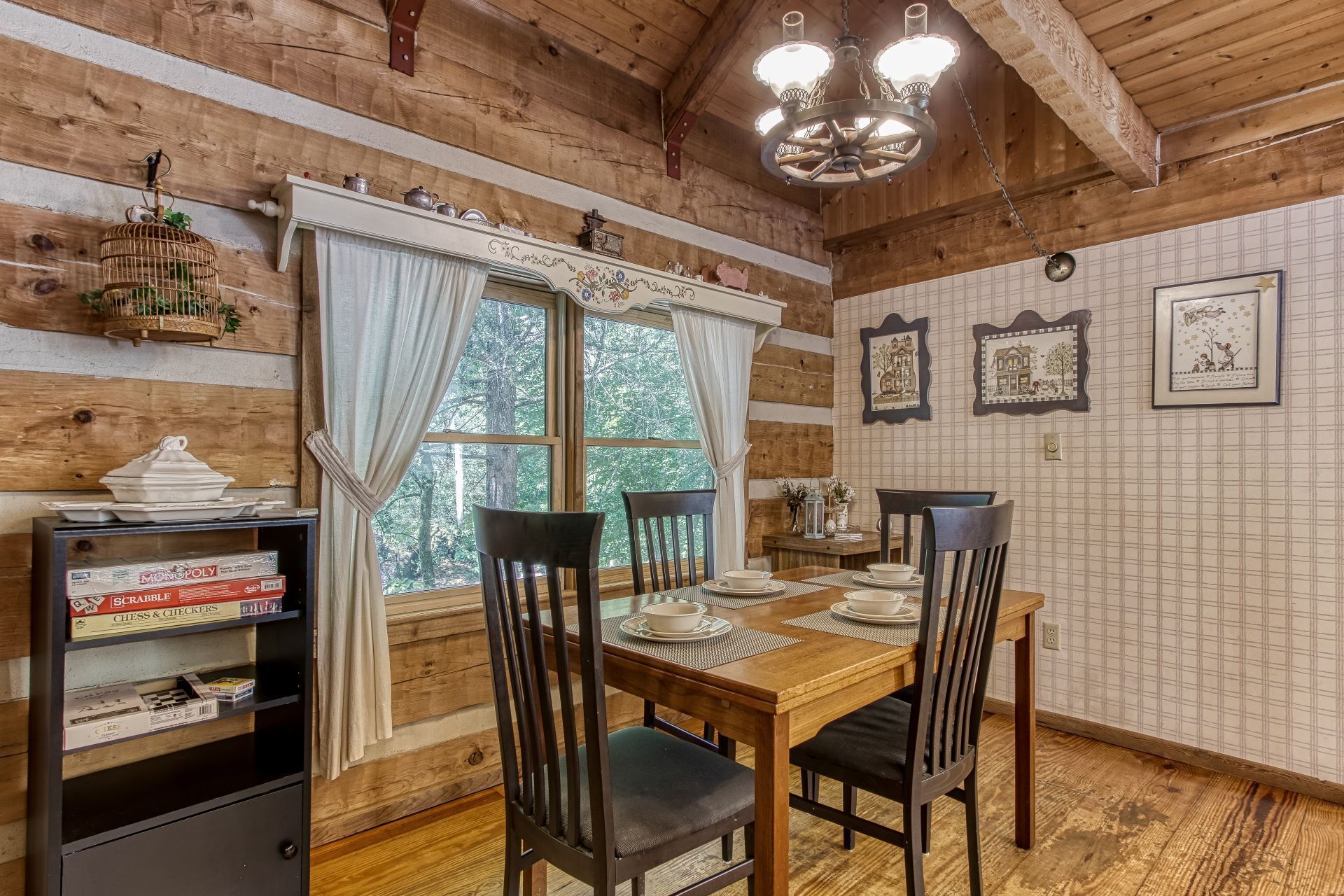 A wooden interior with a dining table set for four, surrounded by chairs.