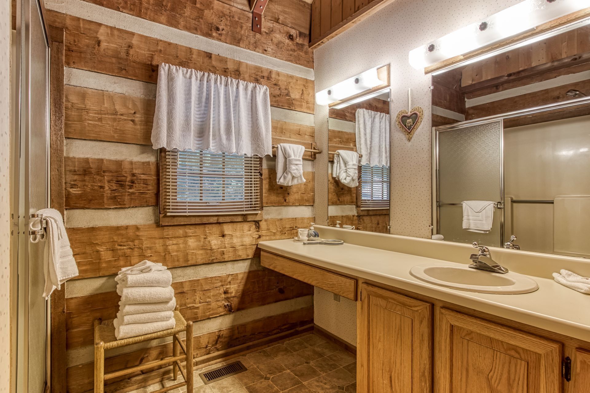 A bathroom with wooden walls, a sink, mirror, and towels.