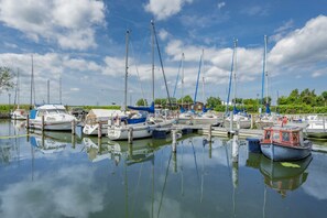 Un port de plaisance où sont amarrés de nombreux bateaux, l’eau est calme et le ciel est dégagé.