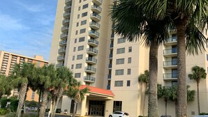 A high-rise hotel with multiple balconies, a red-roofed entrance, and palm trees in the foreground. - Brighton towers.Stay were the view is Beautiful.2 miles to Tanger Outlets!! (Myrtle Beach)