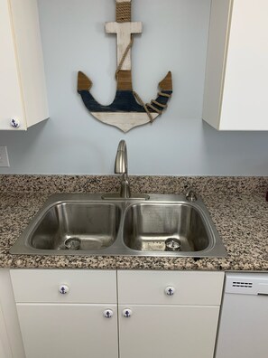 Sink area features a double sink with modern faucet, granite countertop, and white cabinets.