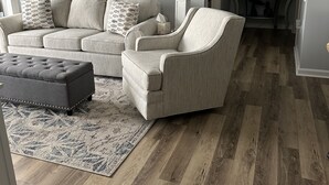 A living room with a sectional sofa, a chaise lounge, and a matching ottoman. A large painting of a beach scene hangs on the wall. - Brighton towers.Stay were the view is Beautiful.2 miles to Tanger Outlets!! (Myrtle Beach)