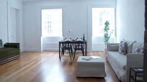 A spacious living room with hardwood floors, a dining table with chairs, a sofa, and a green couch. - Apartment B - Heritage Apartments (Funchal)