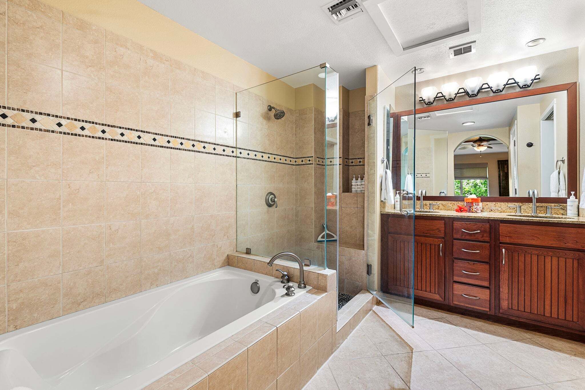 A modern bathroom with a bathtub, shower, and vanity with a large mirror.