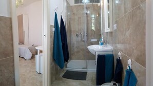 Een moderne badkamer met een glazen douchecabine, een wastafel en een toilet.