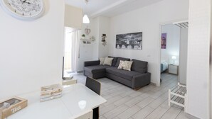 A modern living room with a sectional sofa, a round wall clock, and a minimalist design. - Nicla's Home - Near Trastevere Station (Roma)