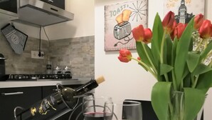 A kitchen with a wine cooler, two wine glasses, and a vase with tulips. - Nicla's Home - Near Trastevere Station (Roma)