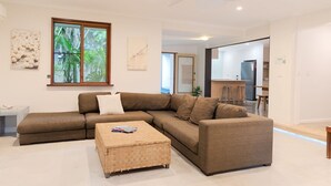 A modern living room with a sectional sofa, a small coffee table, and a ceiling fan. - Beach Cottage Lennox Head (Lennox Head)