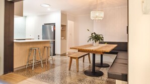 A modern kitchen with a bar area, a wooden dining table, and a bench. - Beach Cottage Lennox Head (Lennox Head)