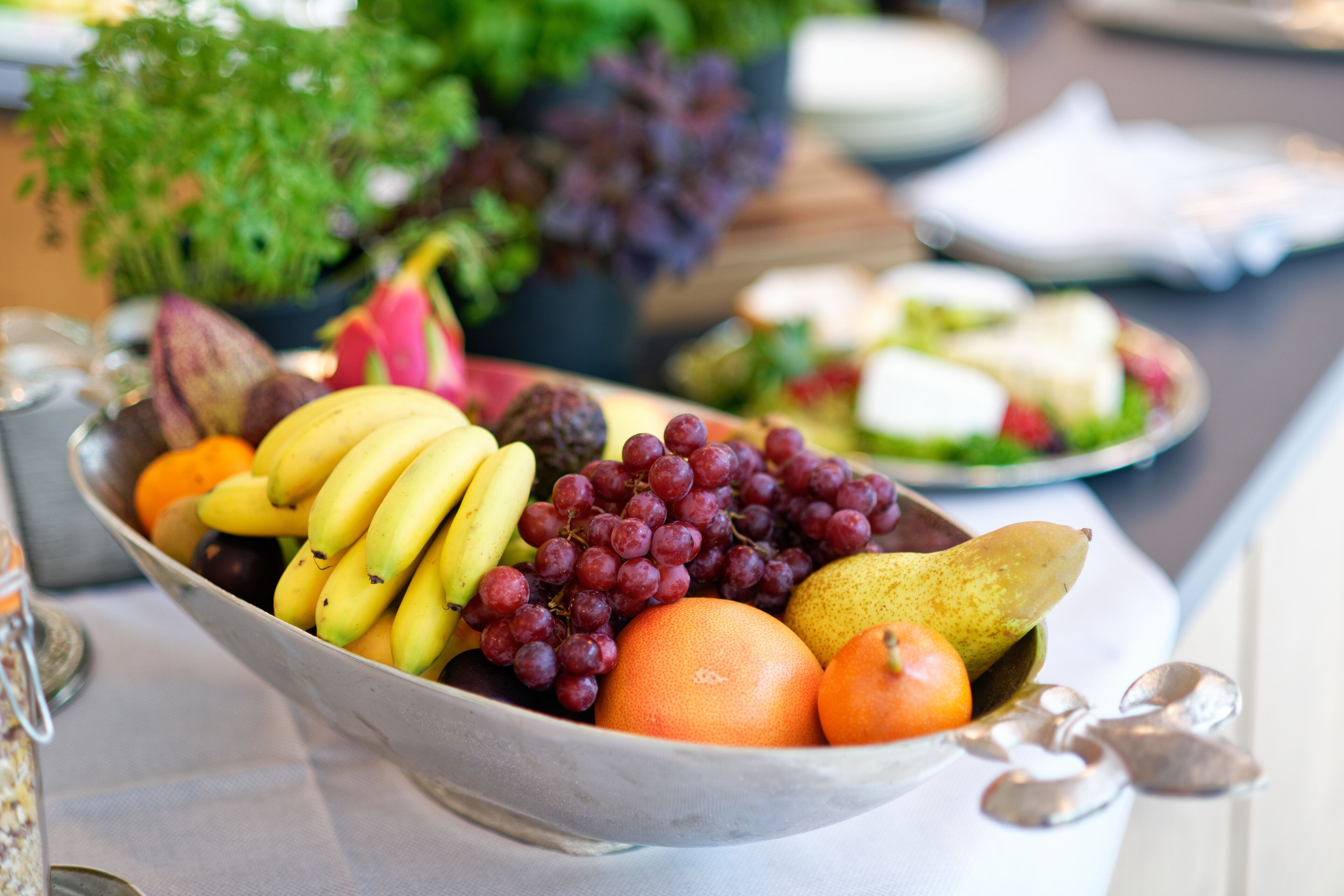 A bowl of assorted fruits including bananas, grapes, oranges, and a pear.