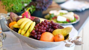 A bowl of assorted fruits including bananas, grapes, oranges, and a pear.