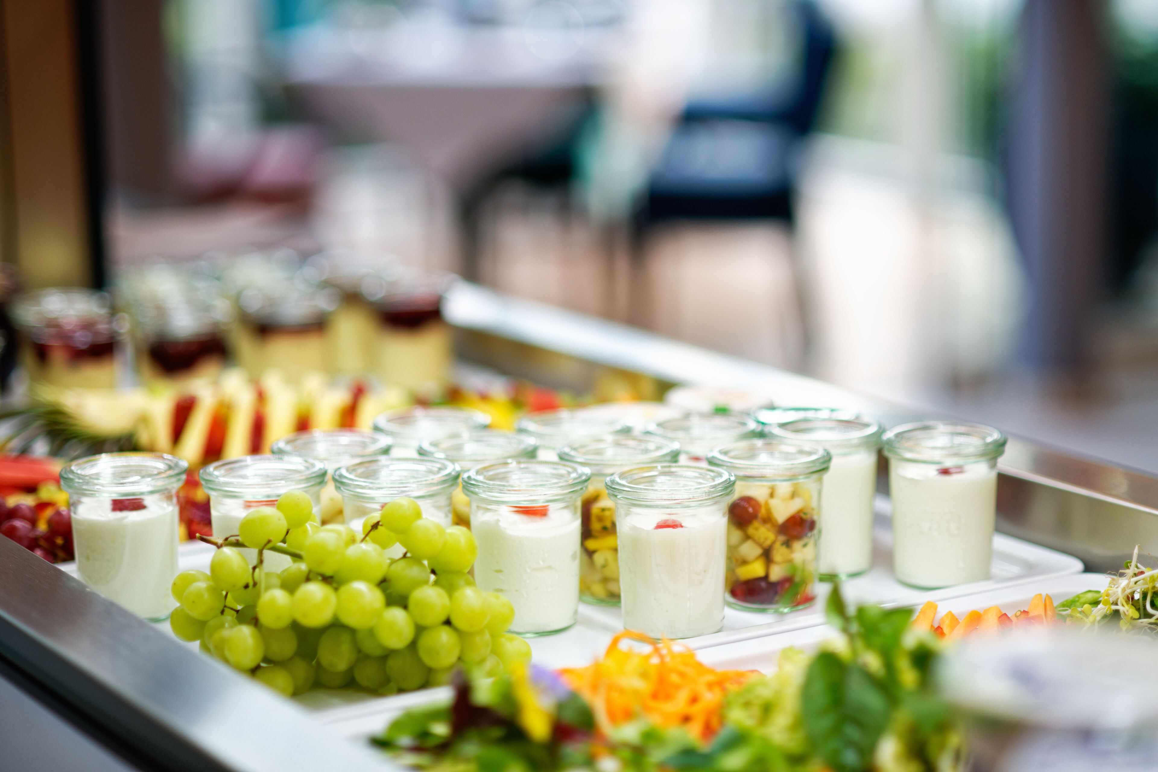 Un bufé con diferentes opciones de comida, como uvas, yogur y ensalada.