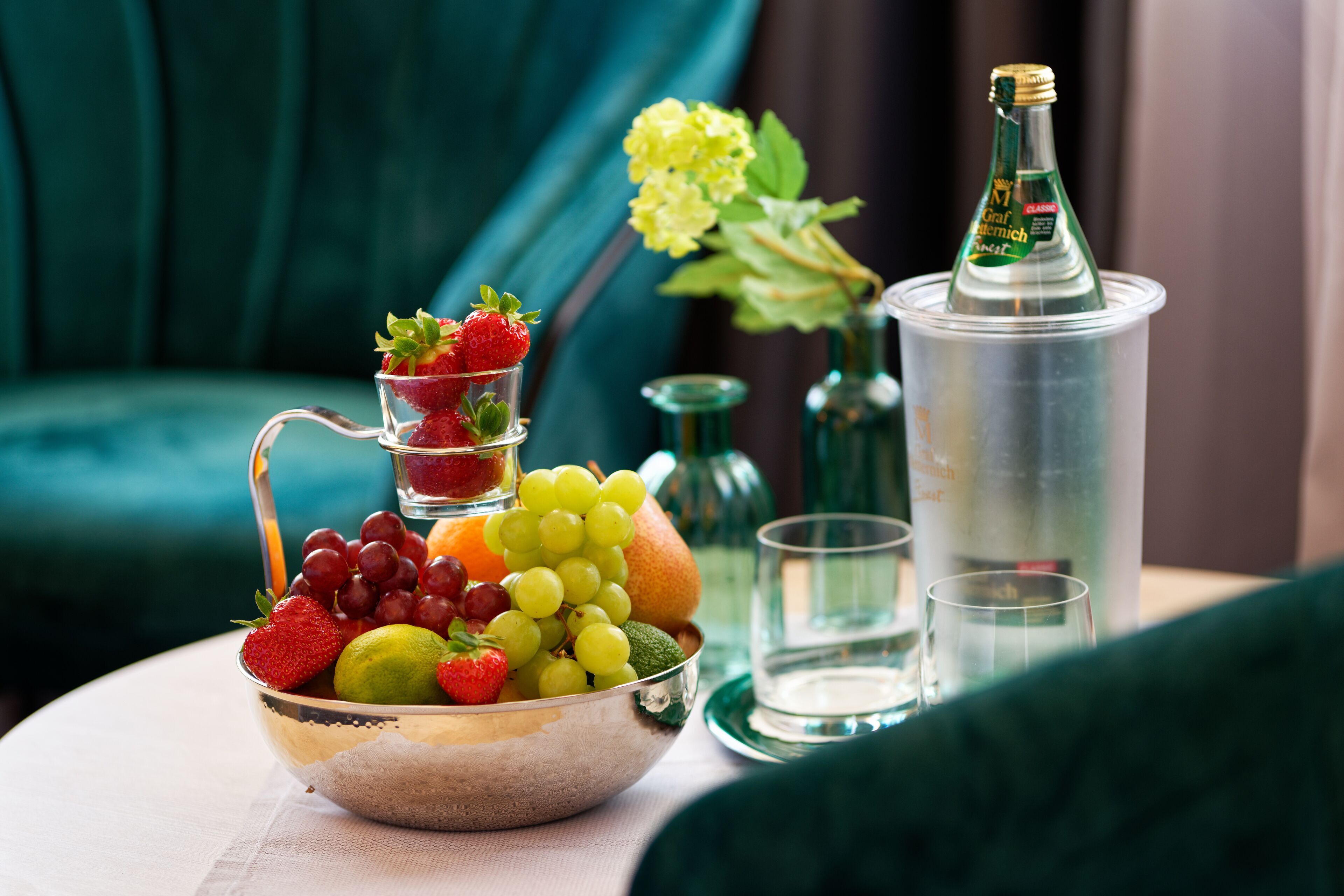 A fruit bowl with strawberries, grapes, and a lime on a table.