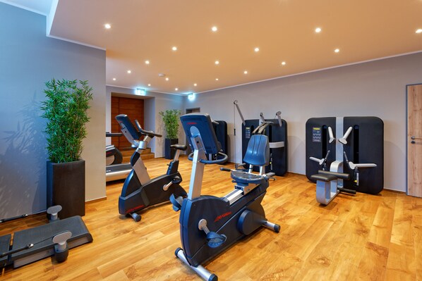 A gym with exercise equipment, wooden flooring, and potted plants. - Stadthotel Borken by Hackmann (Borken)