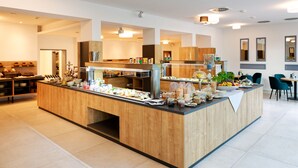 A modern breakfast bar with a variety of food items and a seating area with chairs. - Stadthotel Borken by Hackmann (Borken)