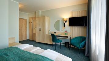A hotel room with two beds, a desk, a chair, a TV, and a wardrobe.