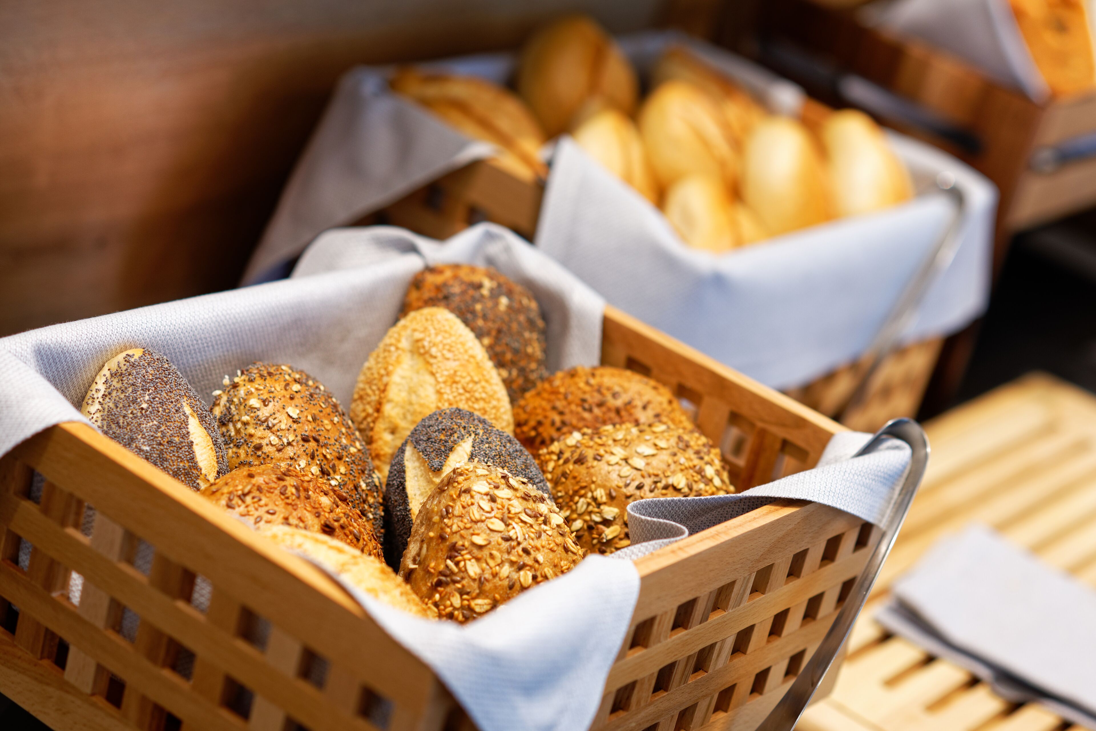 Een houten mand gevuld met verschillende soorten brood, waaronder volkoren en brood met zaden.