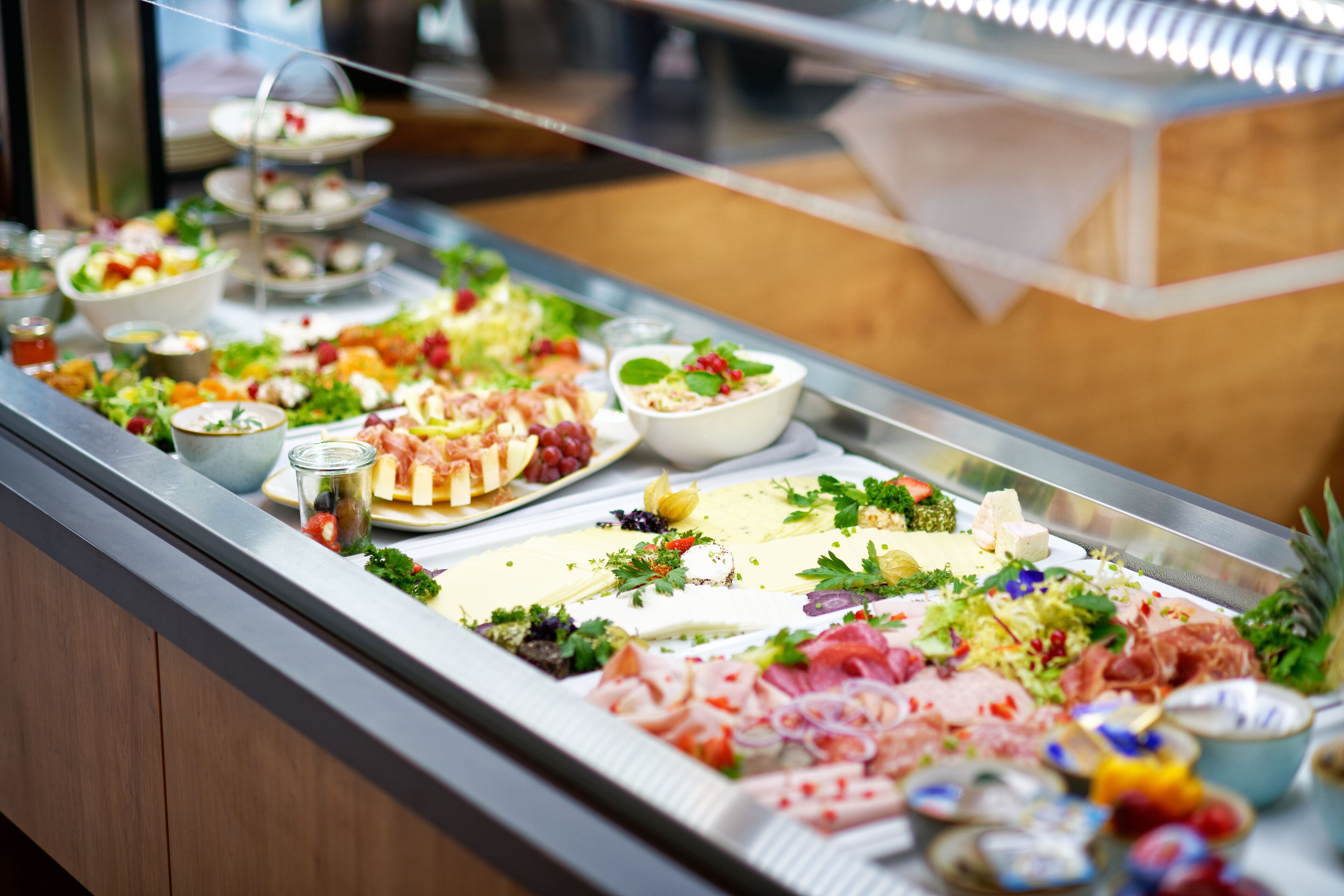 A buffet with various food items including meats, cheeses, and salads.