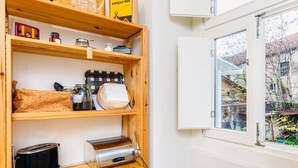 Una cocina con estantes de madera, un tostador, un panero y una ventana con vistas al exterior.