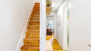 Una escalera de madera que conduce a una habitación con un banco y una estantería con flores.