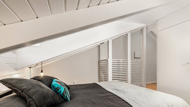 Un dormitorio con cama, mesita de noche y ventana.