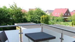 A rooftop terrace with a table and two chairs, surrounded by a metal railing. - Hotel Garni Thule (Wittmund)