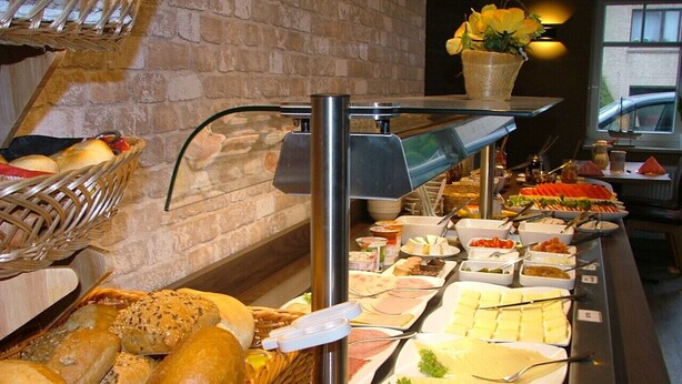A buffet with various food items and bread baskets. - Hotel Garni Thule (Wittmund)