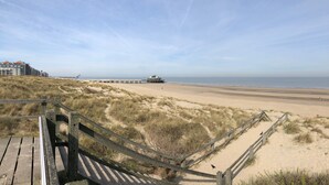 A beach with a wooden boardwalk leading to a pier.