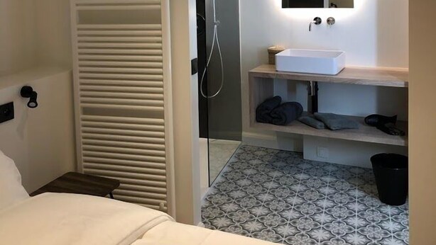 A modern bathroom with a glass shower enclosure, a white sink, and a mirror.