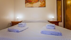 A hotel room with a bed, two nightstands, two lamps, and a painting on the wall. - A33 - Fishermans Cottage in Lagos (Lagos)