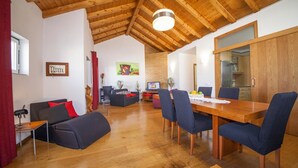 A spacious living area with a wooden ceiling, a dining table with chairs, a sofa, a TV, and a kitchen area with wooden cabinets. - A33 - Fishermans Cottage in Lagos (Lagos)